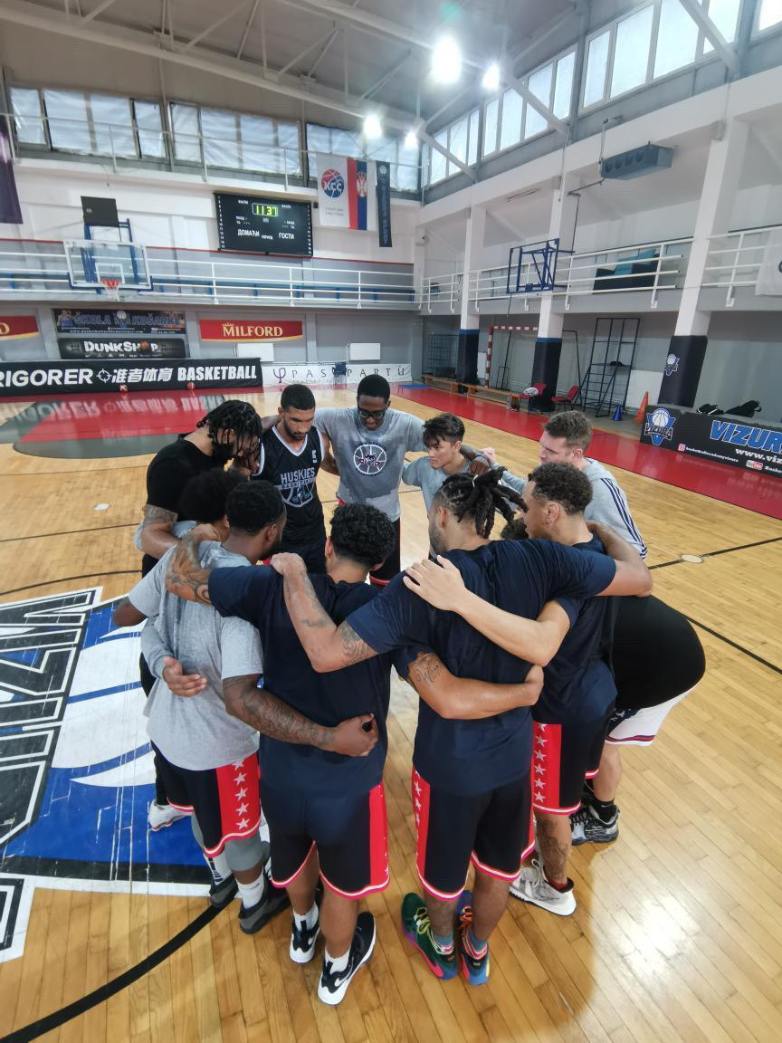Huskies players gather in a team huddle on the court